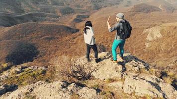 jovem casal caucasiano na montanha de pico cênico aplaude a mão e aprecie o panorama da vista panorâmica. viajar juntos conceito de geórgia. video