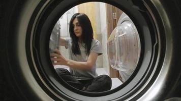 mujer atractiva carga lavadora con ropa para lavar video