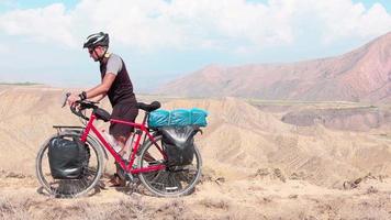 Mann schiebt Fahrradtouren in den Bergen. Alleinreisende Reise mit Fahrradtaschen. Langzeitreisen um die Welt
