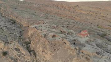 Aerial landing view of Uplistsikhe cave city with rocky terrain during soft sunset light video