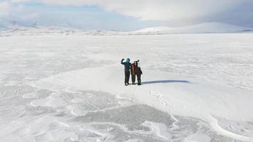 far mor och son tillsammans vinkar till kameran glada med leenden på vintersemester med fantastisk vit landskapsbakgrund video