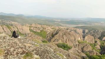 Young caucasian woman sits on rock relaxed enjoying rock formations in background video