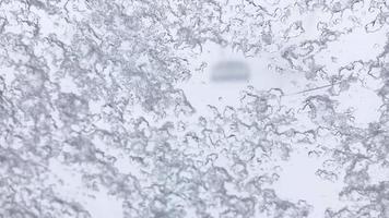 vista ravvicinata dei granuli di neve che cadono sulla finestra all'interno della cabina della seggiovia con forti nevicate e ascensori che passano video