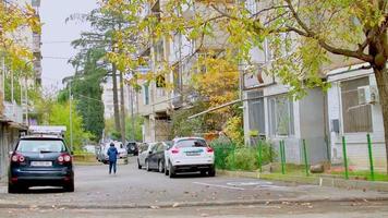 tbilissi, géorgie, 2021 - garçon marchant près de la maison dans le quartier de saburtalo entouré de voitures à tbilissi, géorgie. mode de vie dans le concept du caucase video