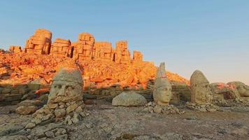statues de vue statique au sommet de la montagne nemrut avec des silhouettes touristiques contre le soleil à adiyaman, en turquie. 4k timelapse matin coucher de soleil côté est nemrut dagi video