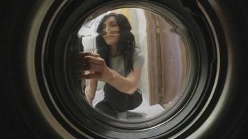 Static view attractive happy woman put clothes to washing machine tub in bathroom. video