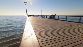 vista statica timelapse pedoni che camminano sul ponte del molo di palanga in una soleggiata giornata estiva. famosi punti di riferimento lituania vacanza vacanza. video