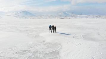 vista cinematográfica família de três pessoas a pé e explorar juntos a bela natureza de inverno. fundo familiar viajante isolado.