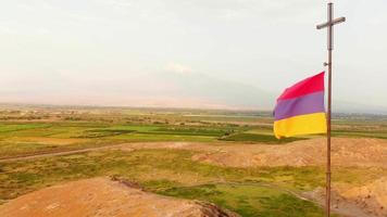 fermer vue aérienne drapeau arménien par temps venteux à l'extérieur avec campagne et fond de montagne ararat video