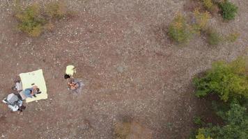 Woman hi-fives man after adding wood to fire in campsite from aerial perspective. video