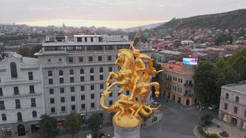 tbilisi, geórgia, 2020 - vista aérea próxima da estátua dourada de st.george com panorama da cidade na praça da liberdade. video