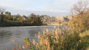 Panning view of Alazani river in autumn surounded by grass and rocky landscape in Mijniskure video