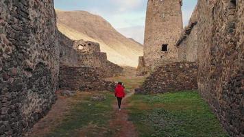 Female tourist walks down the path surrounded by Khertvisi fortress wall ruins. Cinematic filter and travel concept video