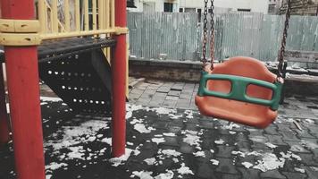 Baby swings swinging with no child in kids playground. Concept of grief and baby loss
