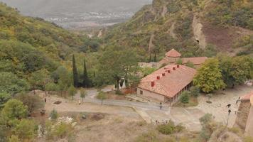 vue aérienne du complexe du monastère de shio-mgvime avec des touristes marchant et une vue panoramique sur la vallée. religion dans le caucase et l'architecture des monastères video