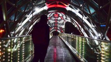 manlig person som passerar på upplyst bro på natten ensam. ensamhet livsstil och singelhuva koncept video