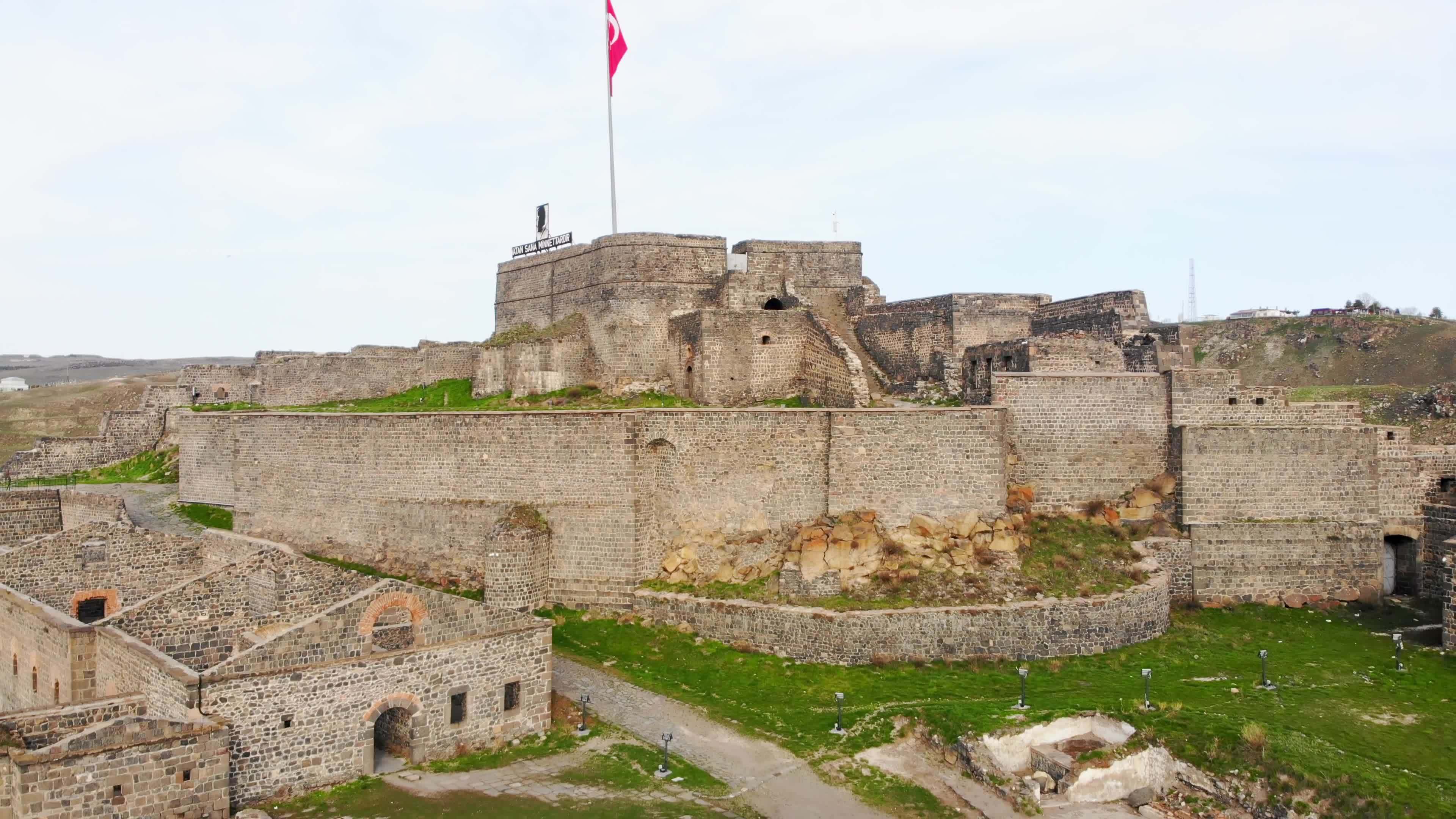 Aerial side ascending view historical famous Kars Castle on meadow hill