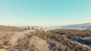Zoom in approaching view of Tbilisi city suburbs panorama surrounded by nature in spring video