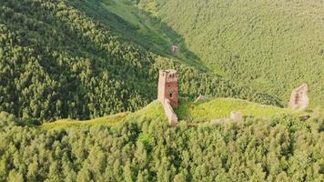 cerchio aereo intorno alle rovine della fortificazione del castello storico di ushguli su per la collina circondata da una natura verde e panoramica. oggetti turistici dello svaneti superiore video