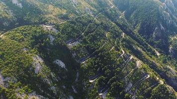 cattaro, montenegro. drone sorvola la serie di serpentine stradali con auto in movimento, circondato dal verde degli alberi video