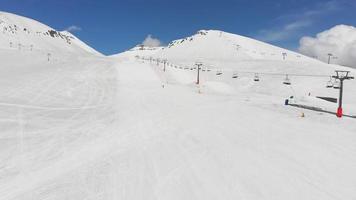 Vorderansicht Ein Skifahrer, der auf der Piste im Skigebiet mit Berghintergrund Ski fährt. leeres skigebiet ende der saison konzept.