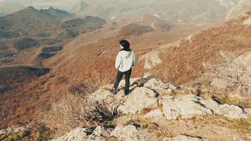 Zoom out aerial side view woman standing on cliff and enjoy panorama. Success and joy of achievement outdoors. video