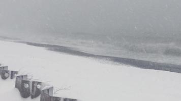 vista de fuertes nevadas en la playa con olas en segundo plano video