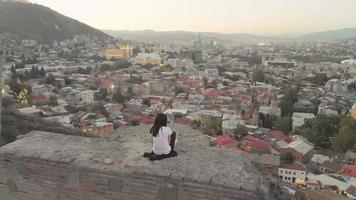 vue révélatrice d'une personne de sexe féminin sur le mur des ruines du château de narikala regardez le panorama panoramique de tbilissi en soirée video