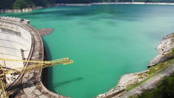 Luftfliege über Kran und grünliches Wasser im Enguri-Dammreservoir. wasserkraft energie und wasserversorgung im kaukasus video