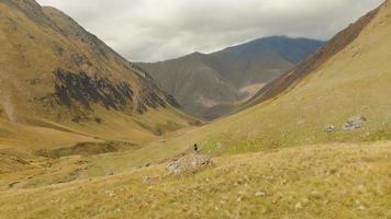 Aerail fly over Female backpacker woman standing on rock and admiring beautiful valley. KAzbegi hiking adventure