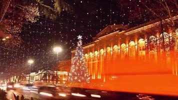 Dynamisches Herauszoomen im Zeitraffer des Tiflis-Weihnachtsbaums im Stadtzentrum und von Autos im abendlichen Berufsverkehr an den Weihnachtsfeiertagen video