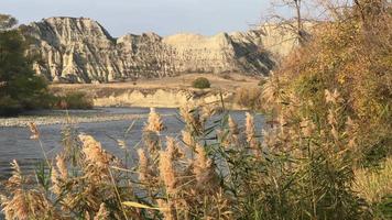 vista del río alazani con hierba en primer plano y acantilados rocosos en segundo plano