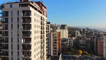 vista aerea in aumento facciate di edifici immobiliari a tbilisi, capitale della georgia in vista autunnale. panorama di sviluppo della grande città della proprietà nella giornata di sole mattutina video