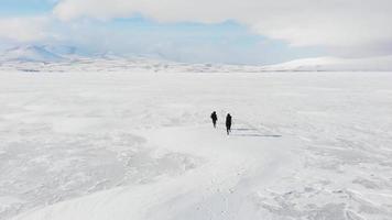 Rückansicht einer glücklichen jungen Frau mit Teenager-Jungen, die spielerisch mit einem malerischen Winterlandschaftspanorama laufen