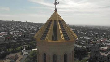 Vista ravvicinata drammatica aerea della cupola della cattedrale della Santissima Trinità con dettagli architettonici con sfondo panorama della città.chiese nel concetto di tbilisi. video