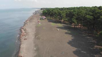 Fast motion aerial ascending fly over black sea beach with cottage houses and polluted beach after the storm video