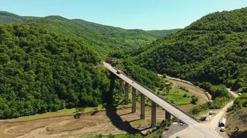 statische luftaufnahme zum weißen lkw, der sich in richtung waldgrün in der kaukasus-bergregion bewegt. logistik- und transportkonzept video