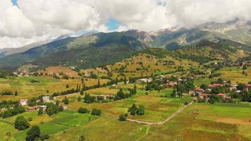 Aufsteigende Luftaufnahme des ländlichen Dorfes Georgia mit Feldern und Bergen im Hintergrund in Swanetien video