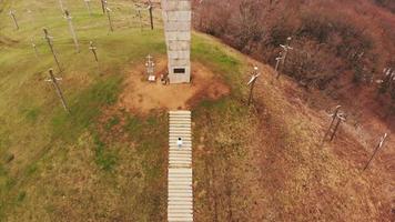 vista aérea inclinada hacia arriba mujer turista subir escaleras en didgori - memorial histórico del sitio de georgia. video