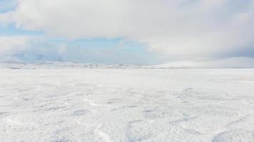 Blick aus Sicht gefrorener eisiger See mit Bergen und dramatischem Himmelshintergrund