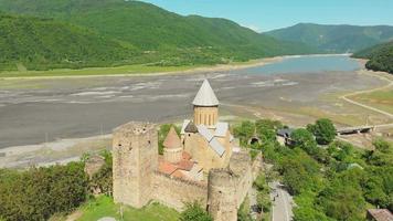 Aerial circle around Ananuri castle complex with tourists walking in summer. KAzbegi national park sightseeing video