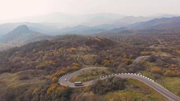 zijaanzicht vanuit de lucht van een vrachtwagen die de heuvel oprijdt met een schilderachtige herfstlandschapsachtergrond video