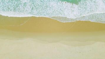 vista aérea da praia de areia e textura da superfície da água. ondas espumosas com céu. bela praia tropical. incrível litoral arenoso com ondas do mar branco. conceito de natureza, marinha e verão. video