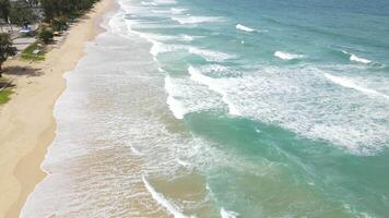 vista aérea de la playa de arena y la textura de la superficie del agua. olas espumosas con cielo. vuelo de drones de una hermosa playa tropical. increíble costa de arena con olas de mar blanco. concepto de naturaleza, paisaje marino y verano. video