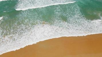 vue aérienne de la plage de sable et de la texture de la surface de l'eau. vagues mousseuses avec ciel. belle plage tropicale. incroyable littoral sablonneux avec des vagues de mer blanche. nature, paysage marin et concept d'été.