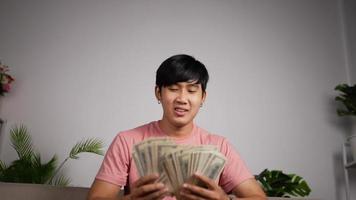 retrato de feliz jovem asiático desfrutar com chuva de dinheiro enquanto trabalhava no escritório. empresário de sucesso recebeu um bônus especial jogando dinheiro como um empresário louco. video