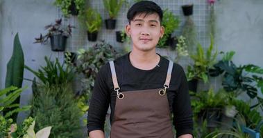 porträt des glücklichen asiatischen männlichen gärtnerbesitzers kreuzt den arm und schaut in die kamera im garten. hausgrün, verkauf online und hobbykonzept.
