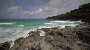 Sea waves crash on the rocks of the coast creating an explosion of water. Foamy waves with sky. Beautiful tropical beach. Amazing Sandy coastline with white sea waves. Nature, seascape and summer. video