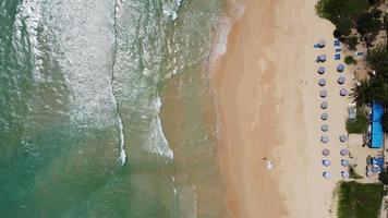 Aerial view of white sand beach and water surface texture. Foamy waves with sky. Beautiful tropical beach. Amazing Sandy coastline with white sea waves. Nature, seascape and summer concept.
