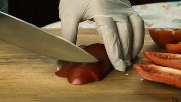 women's hands using a kitchen knife cut fresh red bell pepper on a wooden cutting board. Healthy eating. Chopped red bell pepper